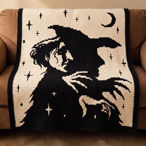 May include: A rectangular crochet blanket featuring a high-contrast black and cream design. The pattern depicts a profile silhouette of a figure wearing a pointed hat, surrounded by a starry night sky motif with a crescent moon in the upper corner.