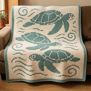 May include: A rectangular crochet blanket featuring a cream-colored background with three teal sea turtles swimming among stylized wave patterns. The blanket is finished with a solid teal border that frames the entire design on all four sides.