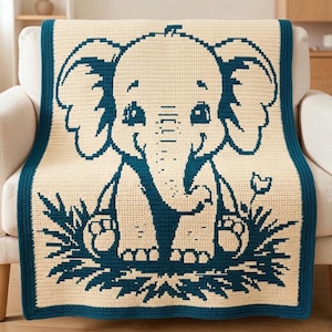 May include: A rectangular crochet blanket featuring a cream-coloured background with a dark teal elephant graphic centred on the fabric. The elephant is depicted sitting in grass with a small flower nearby, framed by a solid dark teal border.
