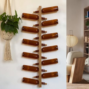 May include: A wooden wine rack mounted on a white wall, holding ten brown glass bottles with cork stoppers. The rack is vertical, with bottles angled for display. Decorative plants in macrame hangers are visible.