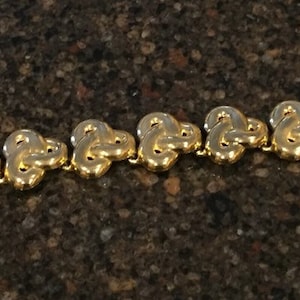 May include: A gold-tone bracelet with a chain made of linked heart-shaped charms.