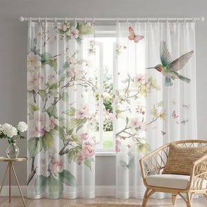 Peut inclure: Rideaux de fenêtre blancs et transparents avec un motif aquarelle de fleurs roses, de feuilles vertes, de papillons et d'un colibri. Les rideaux sont suspendus devant une fenêtre, avec une chaise en osier au premier plan.