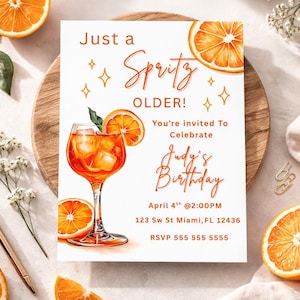 以下が含まれることがあります： オレンジとスプリッツをテーマにした誕生日招待状。「Just a Spritz Older!」と書かれており、日付、時間、場所など、Judyの誕生日の詳細が記載されています。デザインにはオレンジのスライスと、スプリッツカクテルの水彩イラストが含まれています。