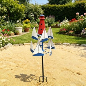 May include: A metal garden spinner featuring a red lighthouse top with black circular windows, mounted on a blue central pole. Below the lighthouse, multiple white and blue sailboat-shaped blades are arranged in a circular, rotating design.