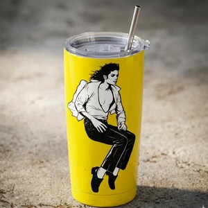May include: A bright yellow stainless steel tumbler with a clear plastic lid and a metal straw. The tumbler features a black and white graphic illustration of a person with long dark hair wearing a white shirt and dark trousers in a seated pose.