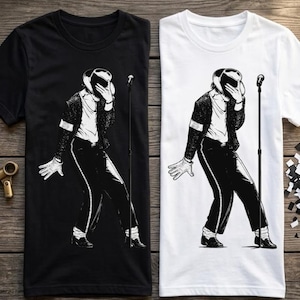 May include: A black t-shirt and a white t-shirt, each featuring a graphic illustration of a performer in a fedora, jacket, and trousers, holding a hand to their face while standing next to a microphone stand on a thin, vertical pole.