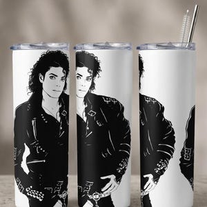 May include: A white cylindrical tumbler featuring a repeating black and white graphic illustration of a person with curly hair wearing a leather jacket with buckles and zippers. The tumbler includes a clear lid and a metal straw with a cleaning brush.