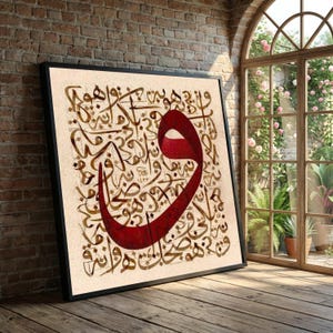 Può includere: Opera d'arte incorniciata con calligrafia araba nei toni del marrone e una grande lettera rosso scuro. L'opera è ambientata su uno sfondo color crema e incorniciata in nero. Il pezzo è appoggiato a un muro di mattoni.