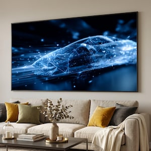 Op de afbeelding: Groot ingelijst kunstwerk met een digitale weergave van een futuristische auto in beweging. Het kunstwerk is overwegend blauw met witte accenten, wat een gevoel van snelheid en technologie creëert. De afbeelding wordt weergegeven boven een beige bank met kleurrijke kussens.