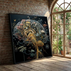 May include: A framed artwork showing a detailed, transparent brain structure filled with colourful flowers and foliage. The artwork is set against a black background, with a black frame. The piece is leaning against a brick wall, with a window and garden visible.
