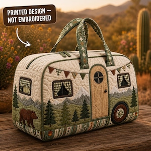 May include: A quilted duffel bag shaped like a vintage camper, featuring a printed design of a brown bear, pine trees, and mountains. The bag has two handles, a zipper closure, and a text label stating: PRINTED DESIGN — NOT EMBROIDERED.