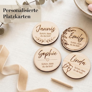 Könnte beinhalten: Vier personalisierte Platzkarten aus Holz mit Namen und dekorativen Elementen. Jede Karte trägt einen anderen Namen: Jannis, Emily, Sophie und Linda. Der Text "Schön, dass du da bist!" ist ebenfalls auf jeder Karte enthalten.