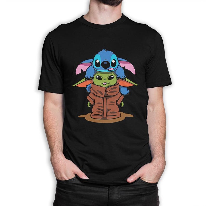 May include: Black t-shirt with a cartoon graphic of Stitch from Lilo & Stitch and Grogu (Baby Yoda) from The Mandalorian. Stitch is blue with large ears, and Grogu is green and wearing a brown coat. The graphic is centered on the shirt.