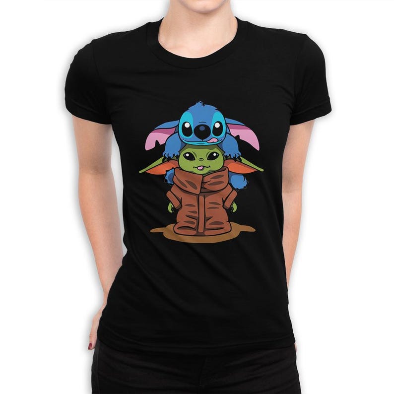 May include: Black t-shirt with a cartoon graphic of Stitch and Grogu. Stitch, in blue, is on top of Grogu, who is wearing a brown coat. The graphic is centred on the shirt.