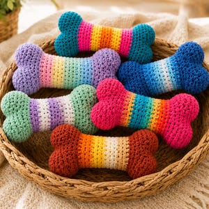 May include: A collection of six crochet dog toys shaped like bones, each featuring distinct horizontal striped color patterns including rainbow, blue gradient, and warm earth tones, all arranged together inside a round woven wicker basket.
