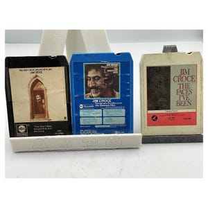 May include: Three vintage Jim Croce 8-track tapes. The tapes are in black, blue, and off-white cases. The black tape reads "You Don't Mess Around With Jim." The blue tape is "Photographs And Memories His Greatest Hits." The off-white tape is "The Faces I've Been."