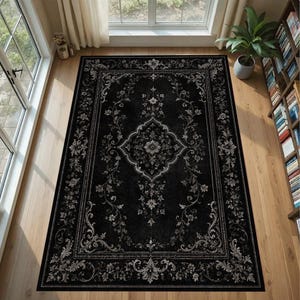 May include: A rectangular area rug featuring a black background with a detailed white and light gray floral damask pattern. The design includes a central medallion surrounded by intricate scrolling vines and a decorative border frame.