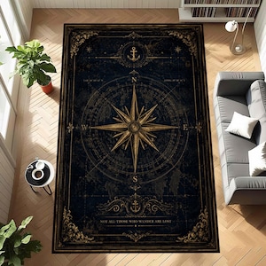 Può includere: Un tappeto rettangolare con sfondo blu navy scuro e una grande rosa dei venti dorata al centro. Il design include icone di ancore, coordinate di navigazione e il testo "NOT ALL THOSE WHO WANDER ARE LOST" in color oro.