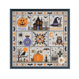 May include: A framed cross-stitch sampler featuring a grid of Halloween-themed icons including a jack-o'-lantern, a haunted house, a witch hat, a broom, spiders, a potion bottle, an owl, a crescent moon, a crow, and ghosts with the text Happy Halloween.