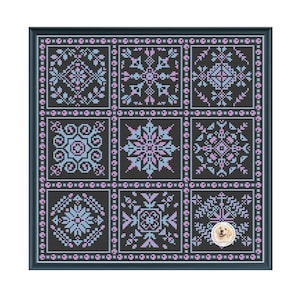 Könnte beinhalten: Ein gerahmtes Kreuzstichstück mit neun quadratischen Tafeln mit komplizierten geometrischen Mustern in Blau-, Rosa- und Weißtönen auf schwarzem Hintergrund. Das Kunstwerk ist in einem dunkelblauen Rahmen eingefasst.