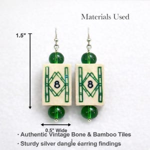 May include: A pair of dangle earrings featuring rectangular bone tiles with green bamboo designs and the number 8. The earrings are 1.5 inches long and 0.5 inches wide, with green beads and silver findings. The text says "Authentic Vintage Bone & Bamboo Tiles."