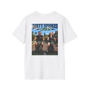 Puede incluir: Una camiseta blanca con un estampado gráfico de dos personas montando bicicletas eléctricas en una carretera pavimentada. El texto dice DIRTY SPOKES CREW en la parte superior, con ONE PASSION ONE RIDE y NO GAS JUST GOOD TIMES, y DIFFERENT BIKES SAME FREEDOM.
