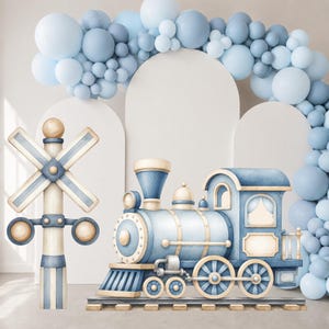 May include: A watercolor-style illustration of a blue and cream steam locomotive train on tracks, positioned next to a matching railroad crossing sign. The scene is decorated with a large arch of various sized light blue balloons.