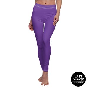 May include: Solid purple leggings featuring a high-rise waistband with visible white stitching along the top seam. The leggings are form-fitting and extend to the ankles, providing a clean, minimalist look with a vibrant, saturated violet color.