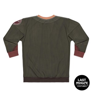 May include: Olive green long-sleeve shirt with brown cuffs and collar trim. The shirt has a circular design on the left shoulder and a brown hem. The back of the shirt is visible. The shirt has the text "LAST MINUTE COSTUMES" on a black circle.