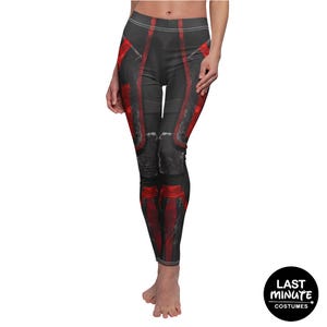 May include: Black and red leggings with a futuristic design. The leggings feature a dark gray base with red accents and panels, creating a bold, armored appearance. The design includes vertical red stripes and geometric shapes.
