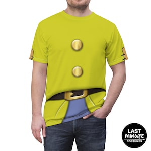 Puede incluir: Una camiseta amarilla con un diseño de disfraz estampado. La camiseta presenta botones dorados grandes, un cinturón negro con hebilla dorada y un panel azul. El texto "LAST MINUTE COSTUMES" está en un círculo negro.