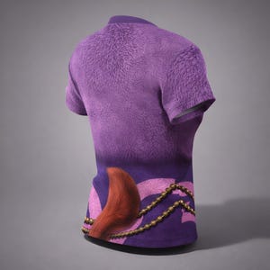 May include: A purple t-shirt with a furry texture on the upper section and a gradient design. The lower part features a stylized design with a red tail, pink accents, and a gold beaded chain. The shirt has short sleeves and a crew neck.