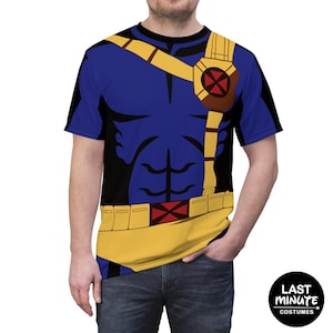Puede incluir: Una camiseta gráfica azul y amarilla con un diseño de disfraz de superhéroe. La camiseta tiene un torso azul con correas y detalles de cinturón amarillos. El diseño incluye un emblema marrón y rojo en el pecho. La camiseta es un disfraz de Last Minute Costumes.