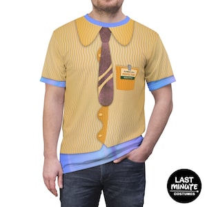 May include: A short-sleeved t-shirt featuring a printed design of a yellow button-down shirt with a brown tie, a chest pocket, and an Element City Inspector badge that reads Wade Ripple. The shirt has a light blue collar and sleeve trim.