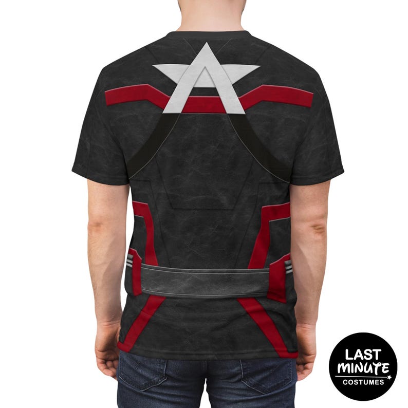 Puede incluir: Camiseta negra con un dise&ntilde;o gr&aacute;fico que se asemeja a un disfraz de superh&eacute;roe. El dise&ntilde;o incluye una estrella blanca y la letra "A" en la parte superior, con rayas rojas y un cintur&oacute;n gris en el pecho. La camiseta la lleva una persona.