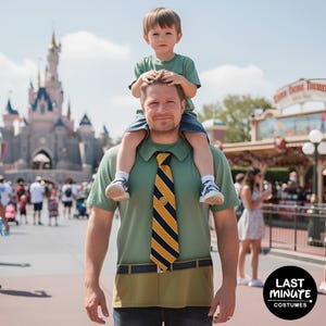 Puede incluir: Un hombre con un disfraz de camiseta verde con una corbata a rayas amarillas y azul marino y un diseño de pantalón caqui, con un niño sobre sus hombros. Un castillo y personas se ven al fondo.