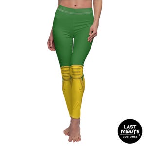 May include: Green leggings with yellow knee pads, a costume design. The leggings have a high waist and a white stripe at the top. The knee pads are a light yellow color with a darker yellow design. The Last Minute Costumes logo is in the bottom right corner.