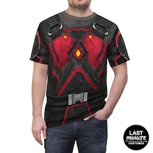 Puede incluir: Camiseta gráfica negra y roja con un diseño de armadura futurista. La camiseta presenta un patrón detallado con un acento amarillo en forma de diamante y hebillas plateadas. El diseño está impreso en una camiseta gris. Colección Last Minute Costumes.