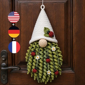 May include: A crochet gnome wall hanging featuring a tall, off-white pointed hat adorned with a green leaf and a red ladybug. The gnome has a round beige nose and a long, curly green beard decorated with small white flowers and red ladybugs.