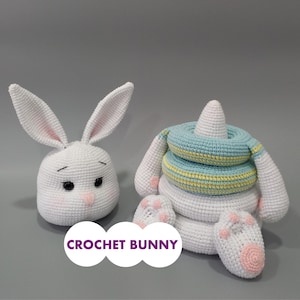 Può includere: Due giocattoli a forma di coniglietto all'uncinetto. Uno è una testa di coniglio bianca con interno orecchie rosa e naso rosa. L'altro è un giocattolo impilabile bianco con anelli blu e gialli e zampine di coniglio. Il testo "CROCHET BUNNY" è in basso.