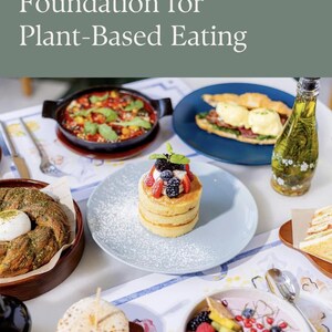 Op de afbeelding: Een tafelsetting met diverse plantaardige gerechten. Een stapel pannenkoeken met bessen en poedersuiker ligt op een lichtblauw bord. Andere gerechten zijn een groenteschotel, een croissant sandwich en een fruitschaal.