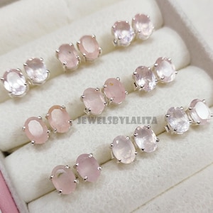 Peut inclure: Six paires de boucles d'oreilles à clous en quartz rose de forme ovale, montées sur des griffes en argent. Chaque paire présente des pierres précieuses rose pâle translucides à facettes. Le texte JEWELSBYLALITA est visible sur le présentoir.