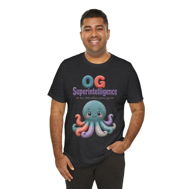 May include: A dark charcoal gray short-sleeve t-shirt featuring a graphic of a teal octopus with multicolored tentacles. The text reads "OG Superintelligence" in blue and purple, with "Est. 300 million years ago" printed in small orange letters.
