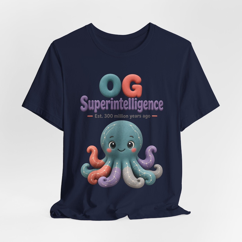 May include: A navy blue short-sleeve t-shirt featuring a graphic of a teal octopus with constellation patterns on its tentacles. Above the octopus, the text reads "OG Superintelligence" and "Est. 300 million years ago" in colorful, rounded lettering.