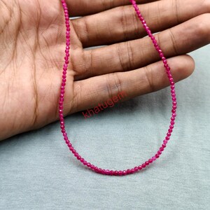 May include: A delicate necklace composed of small, faceted, hot pink gemstones. The necklace is displayed against a neutral background, showcasing the vibrant color and intricate details of the beads. The necklace is a fine jewelry piece.