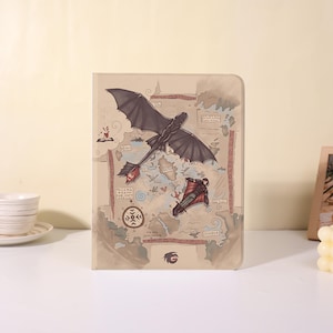 May include: A beige notebook featuring a map design with illustrations of a black dragon and a person in a red and black suit. The notebook has a dragon logo at the bottom and text in the image.