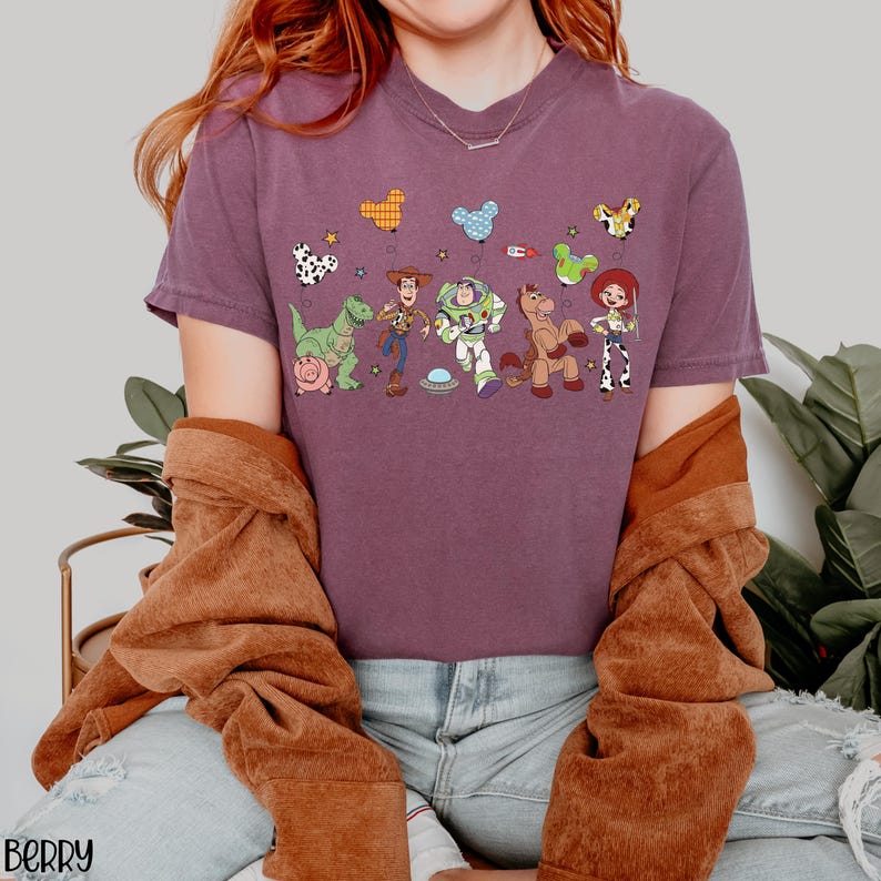 Puede incluir: Una camiseta de manga corta color baya con un estampado gr&aacute;fico de los personajes de Toy Story, incluyendo a Woody, Buzz Lightyear, Jessie, Rex, Bullseye y Hamm. El dise&ntilde;o incluye varios globos con forma de Mickey Mouse y estrellas.