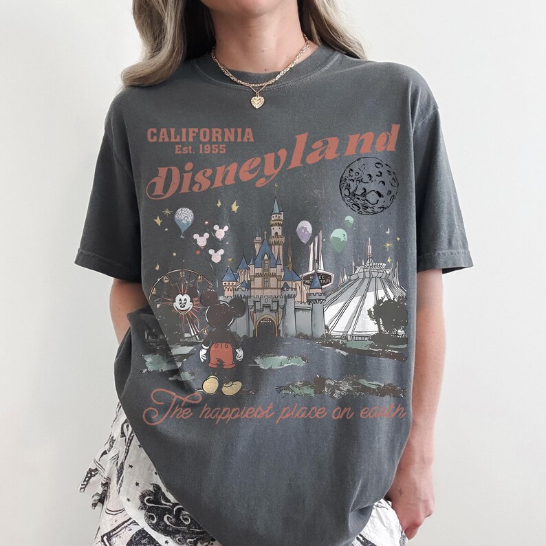 May include: Dark gray t-shirt with a Disneyland graphic. The design includes the Disneyland logo, a castle, Mickey Mouse, a Ferris wheel, and the text "The happiest place on earth."