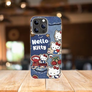Puede incluir: Una funda de tel&eacute;fono con un dise&ntilde;o similar al denim y gr&aacute;ficos de Hello Kitty. La funda incluye el texto "Hello Kitty" y varias ilustraciones del personaje, junto con cerezas y una balanza.