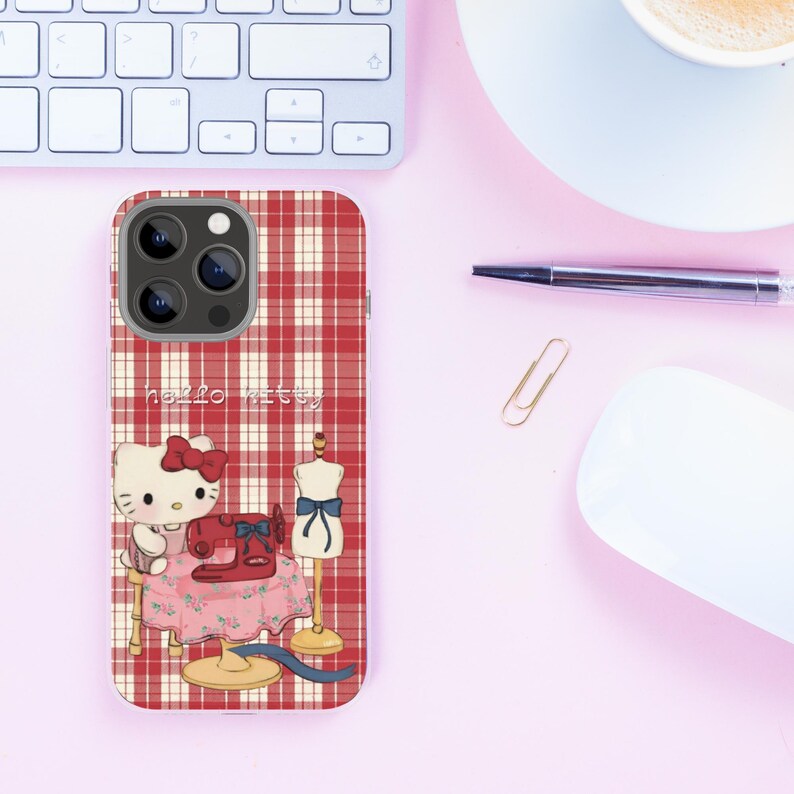 Puede incluir: Una funda de tel&eacute;fono a cuadros rojos y blancos con un dise&ntilde;o de Hello Kitty. La ilustraci&oacute;n muestra a Hello Kitty con una m&aacute;quina de coser, un maniqu&iacute; y el texto "hello kitty".
